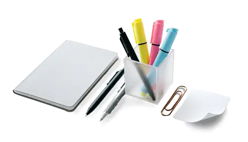 A neatly arranged set of office supplies on a white desk, including a small lined notebook, three pens, a clear container of colorful highlighters, a large paper clip, and a stack of white sticky notes.
